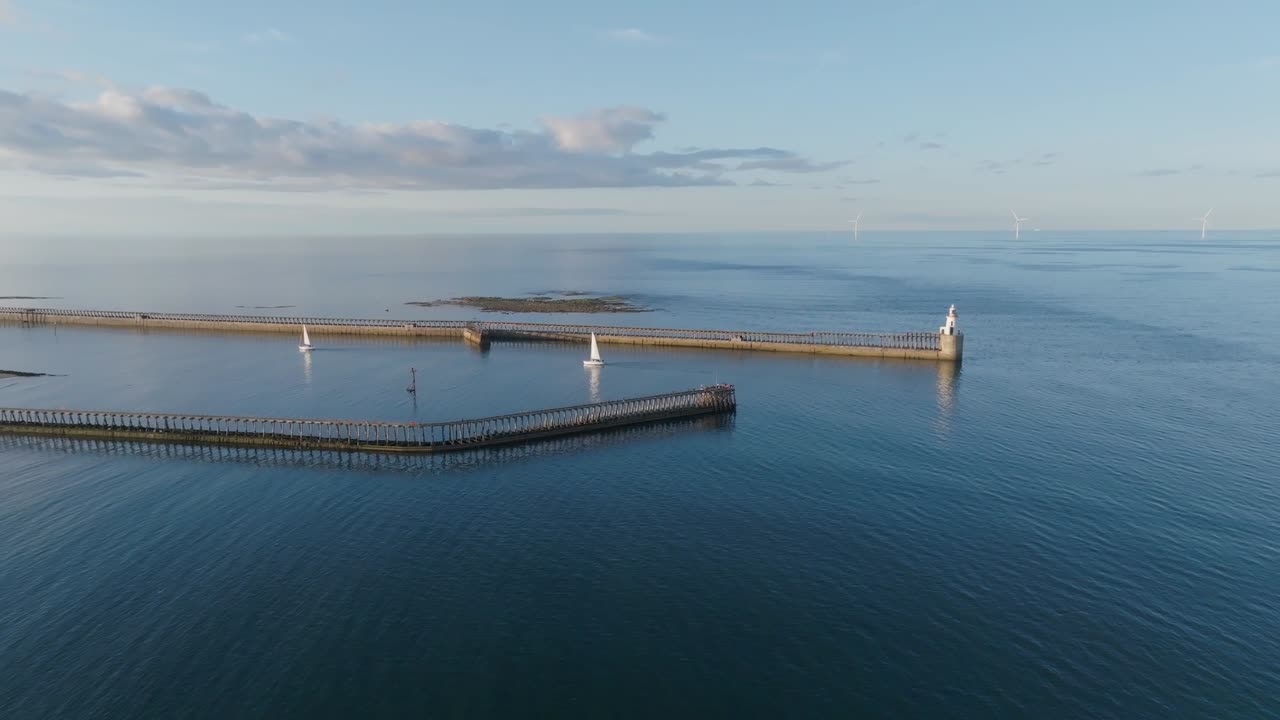Two sail boats entering Northumberland harbour on calm summer evening