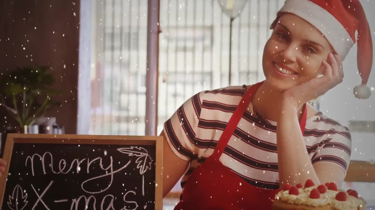 composición de video con nieve cayendo sobre chica feliz en sombrero de santa con pizarra en la tienda