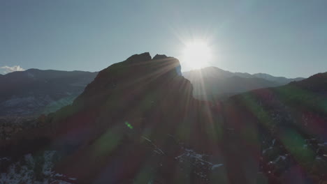 aerial dolly forward toward red rock silhouette with sun spot