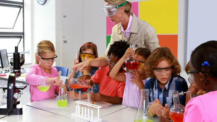 Skolelærer hjælper skolebørn med kemisk eksperiment i laboratoriet