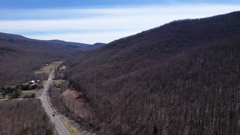scenic hillside near barns and woodland forests with a winding highway set along the bottom of the valley