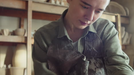 female sculptor working on clay head in workshop