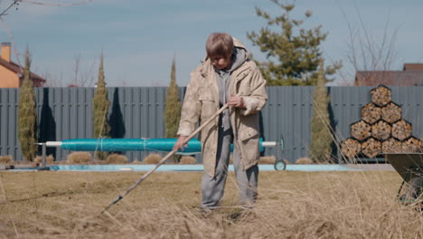 Senior woman raking leaves in the garden