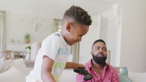 feliz padre e hijo afroamericanos viendo jugar videojuegos juntos, en cámara lenta
