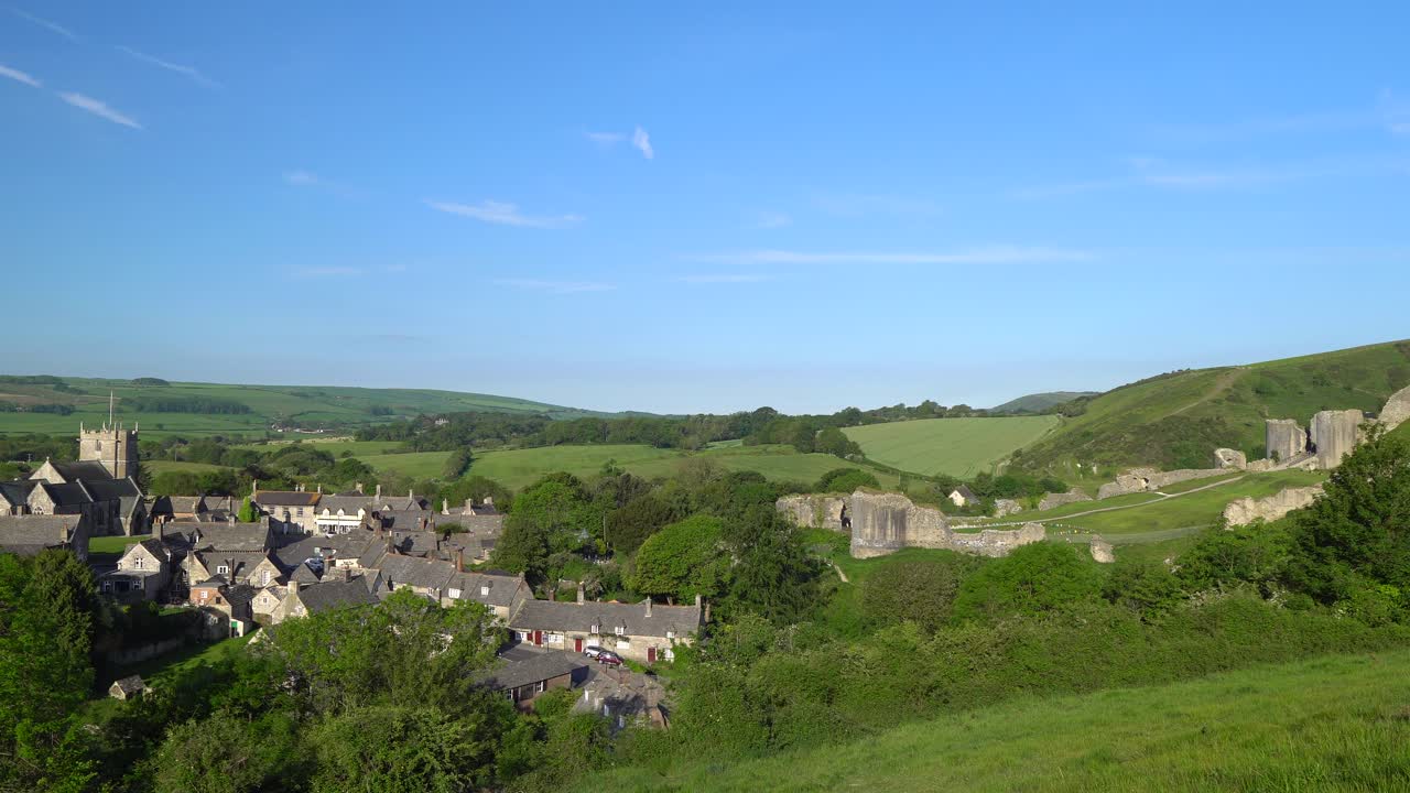 İngiltere, Dorset, Purbeck Adası'ndaki Corfe köyü ve kalesinin sabahın erken saatlerinde yavaş panoramik çekimi.