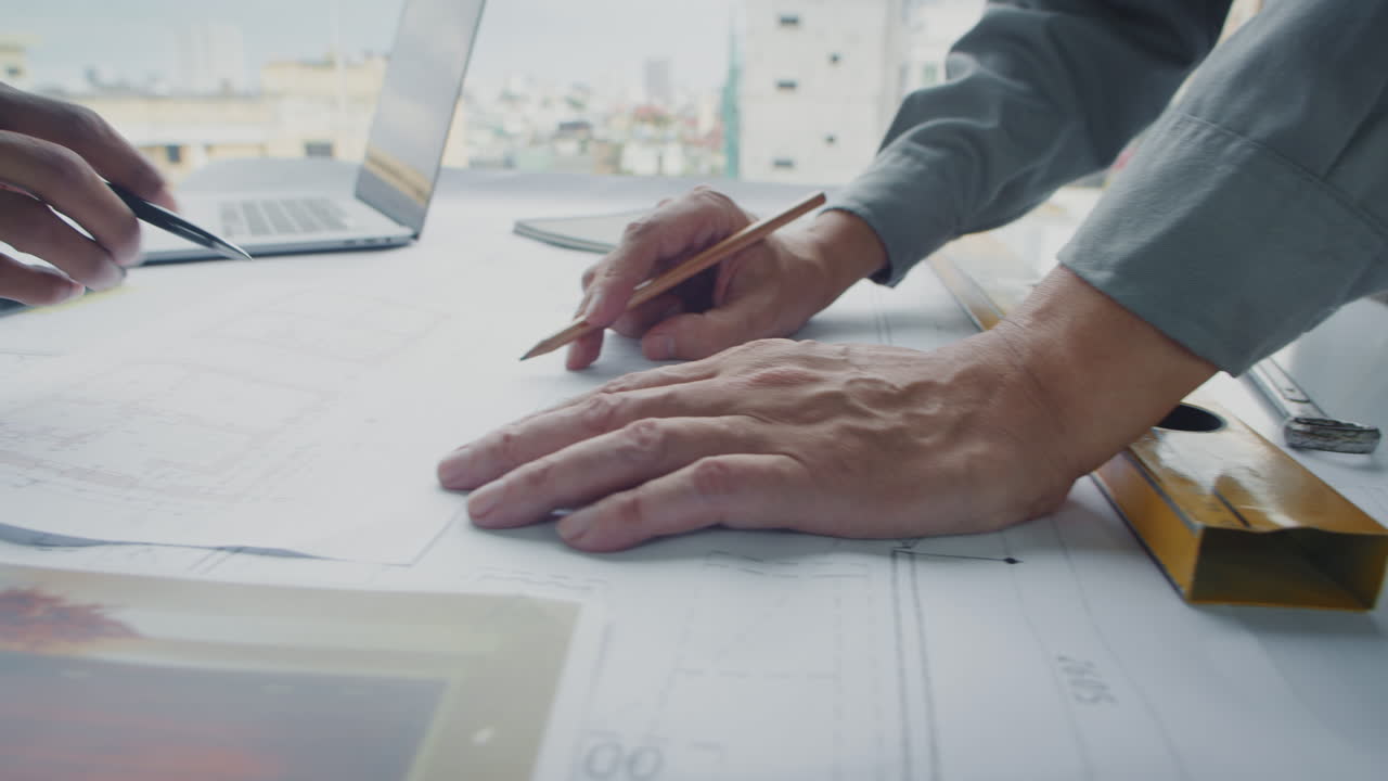 Unrecognizable Engineers Writing Measurements of Room on Blueprint