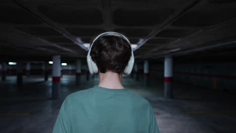person with headphones in an empty underground parking garage