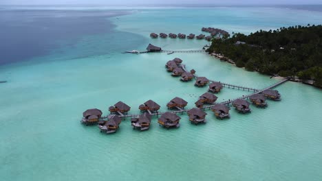 Aerial-orbits-Polynesian-style-over-water-villa-cabanas,-Taha'a-Island