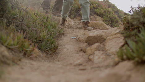 close up of two unrecognizable hikers walking on mountain terrain