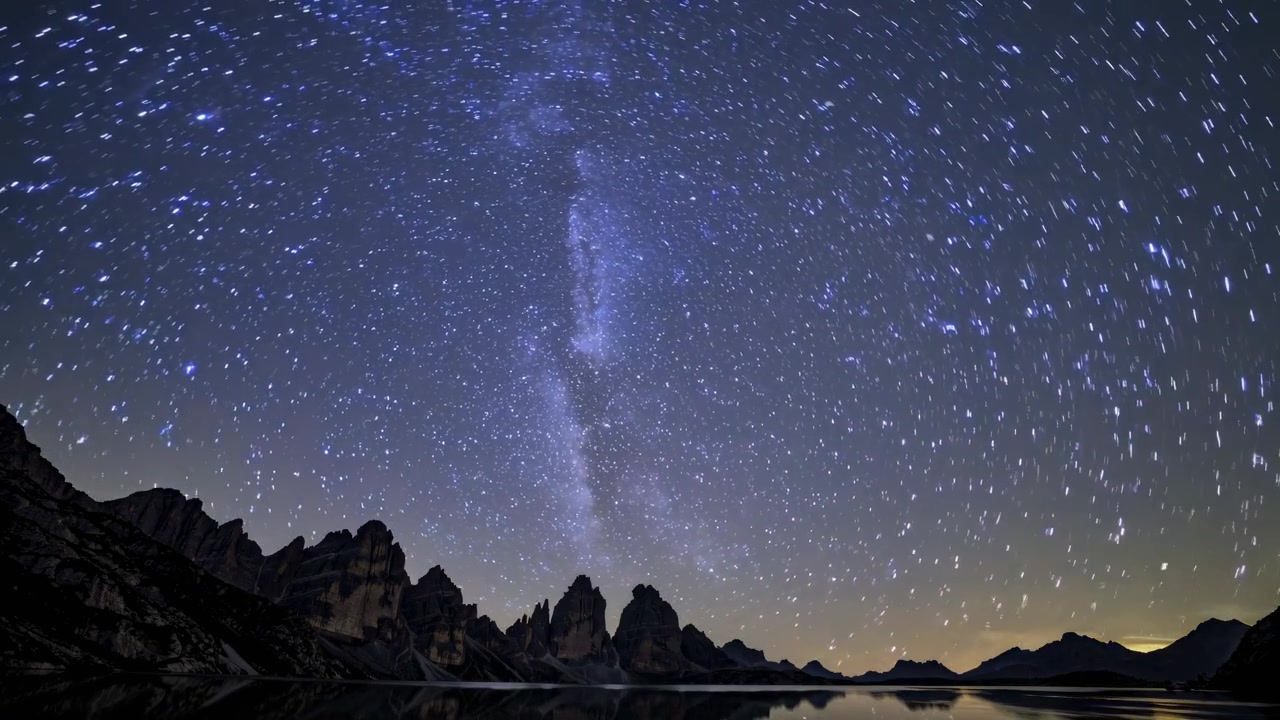 山の湖上での天の川と星の軌跡のタイムラプス
