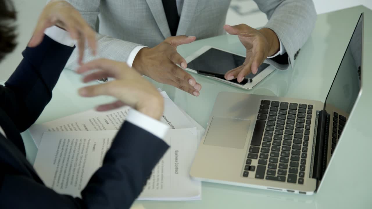 Profesionales sentados en su lugar de trabajo y gesticulando.