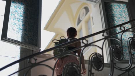 woman climbing spiral staircase in historic building with stained glass windows