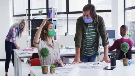 diversos colegas de oficina masculinos y femeninos con máscaras faciales discutiendo sobre el plan de diseño en moder