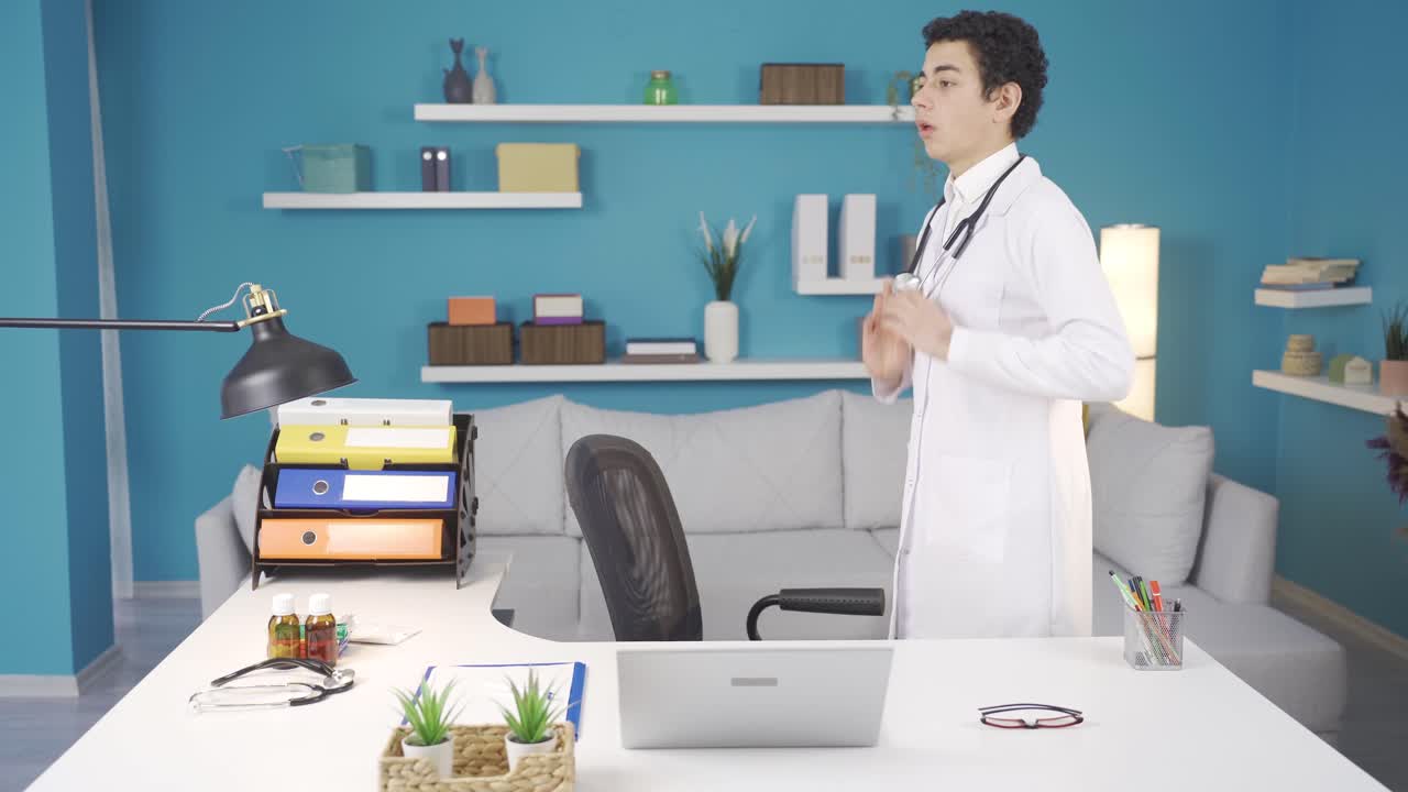 医師の制服とステトスコップを着た面白い少年が 医師の両親の作業テーブルに座っています