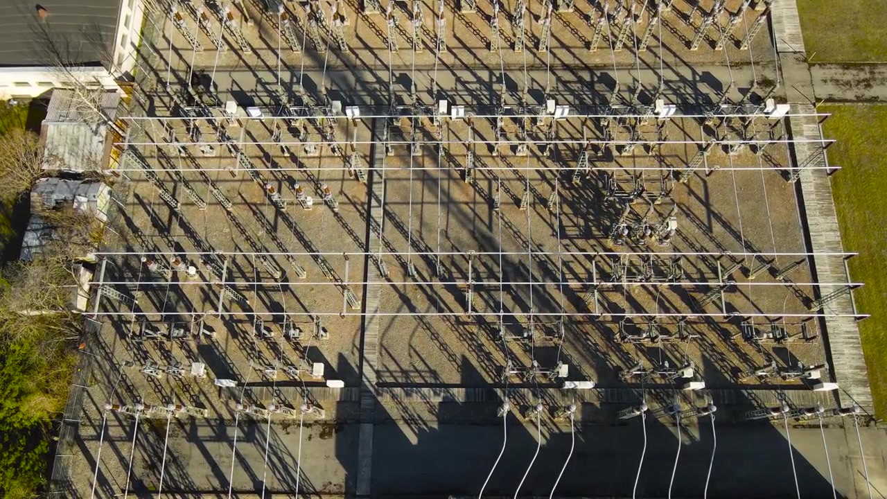 High voltage electrical substation with transformers and power lines for energy transmission, an industrial complex for converting and distributing electricity seen from a drone on a sunny day