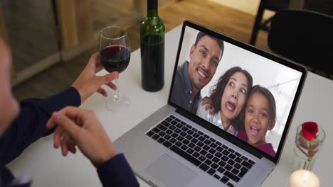 Mid-section-of-african-american-woman-drinking-wine-while-having-a-video-call-on-laptop-at-home