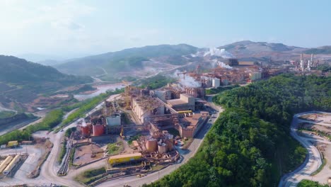large mining and processing infrastructure surrounded by hills at barrick gold site in cotuí, dominican republic. aerial orbit, approaching view