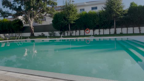 beautiful big turqouise outdoor swimming pool with small birds flying over the water in sunny portugal