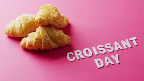 Video-of-close-up-of-croissants-and-croissant-day-text-on-pink-background