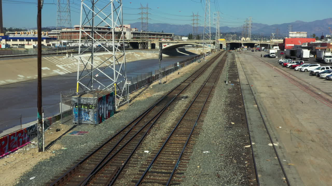 Low flying over empty train tracks running parralell to the LA River in Downtown Los Angeles during a clear Blue Sky Day, Drone, California, USA