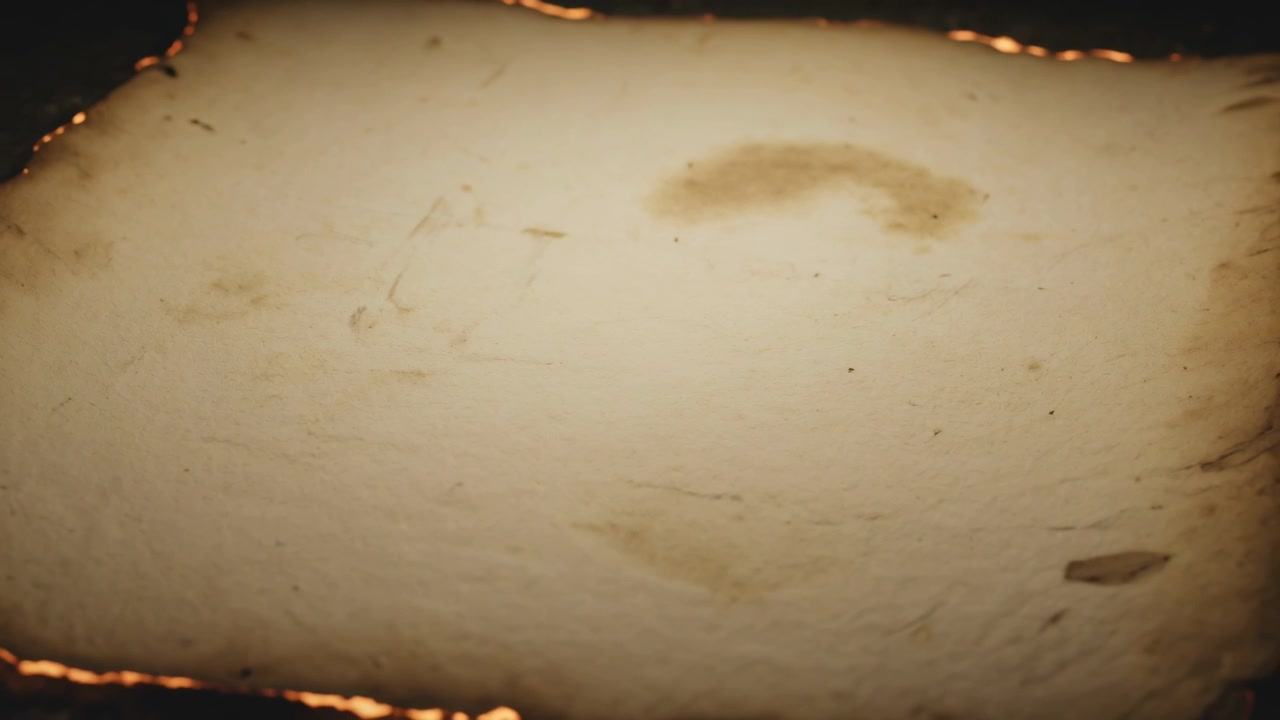 Bordi di carta invecchiata che bruciano, partendo da punti incandescenti su una superficie scura, formando carbonella e braci.