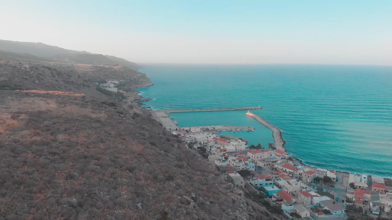 drone volando hacia un pequeño pueblo en grecia
