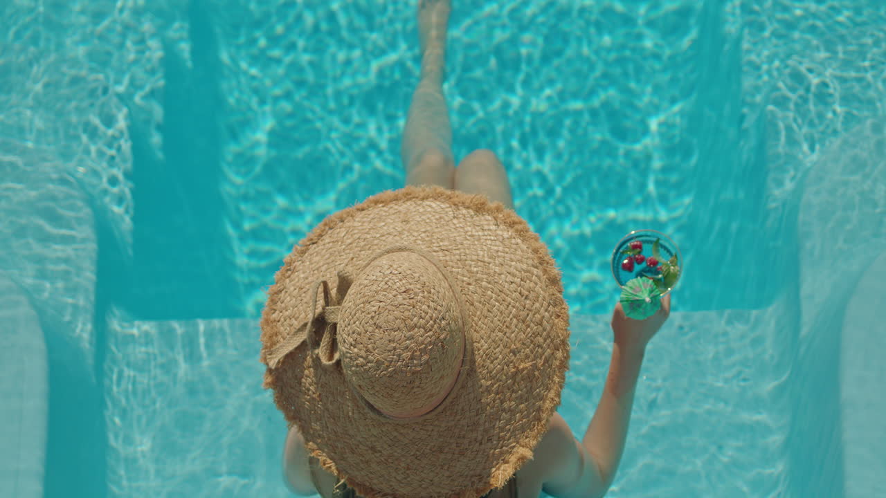 Donna che si rilassa in piscina con un cocktail