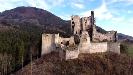 ruins of a medieval castle from the front of a drone in the middle of the mountains of a slovakian landscape