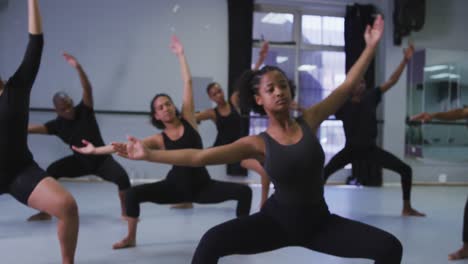 multi-ethnic group of fit male and female modern dancers practicing a dance routine