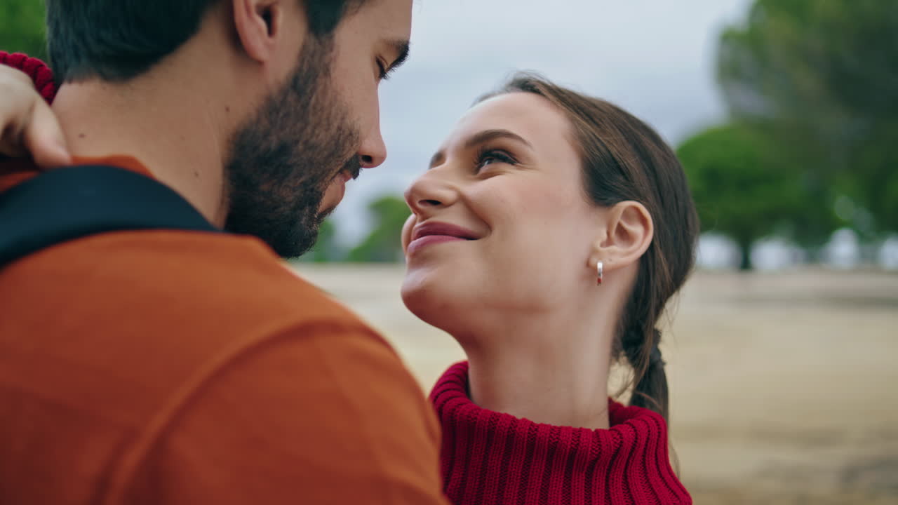 Ritratto verticale: bella coppia nella natura. Uomo felice che bacia il naso della donna sorridente.