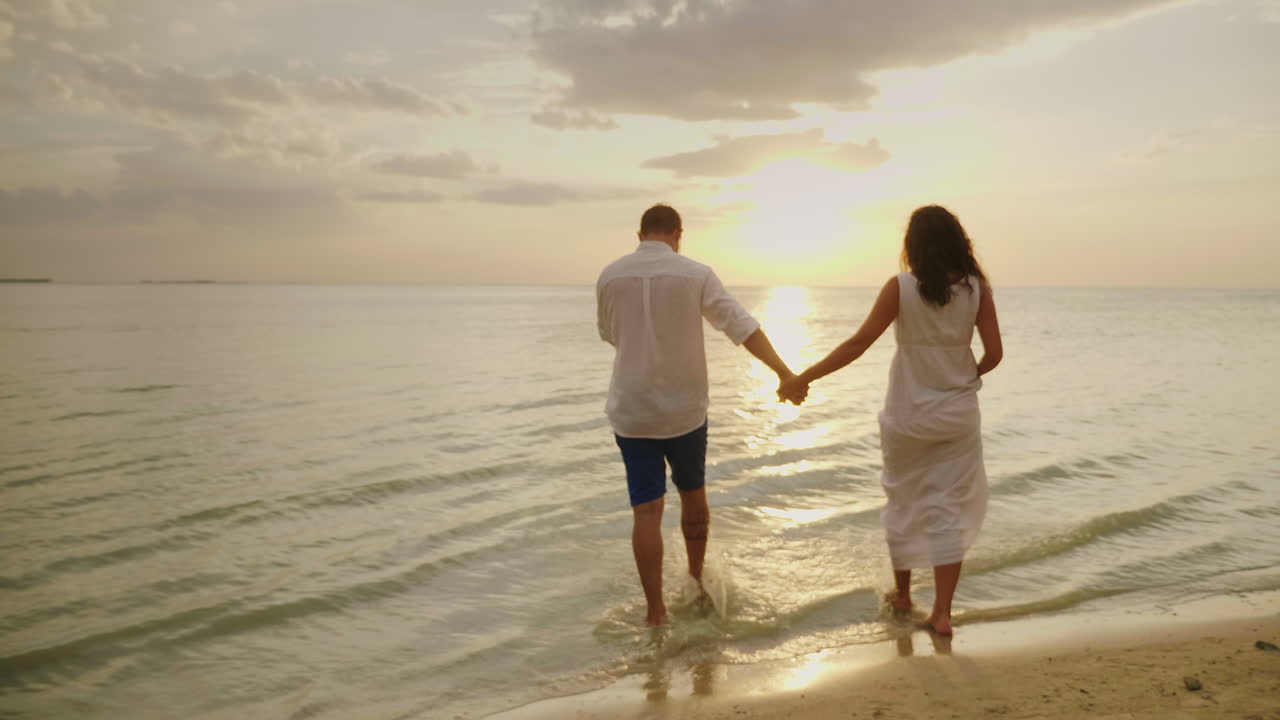 Young Couple In Love In Light Clothes Carefree Running On A Clean Tropical Beach