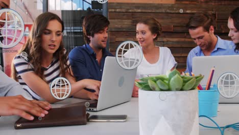 Animation-of-multiple-globe-icons-over-diverse-coworkers-discussing-reports-in-meeting-at-office