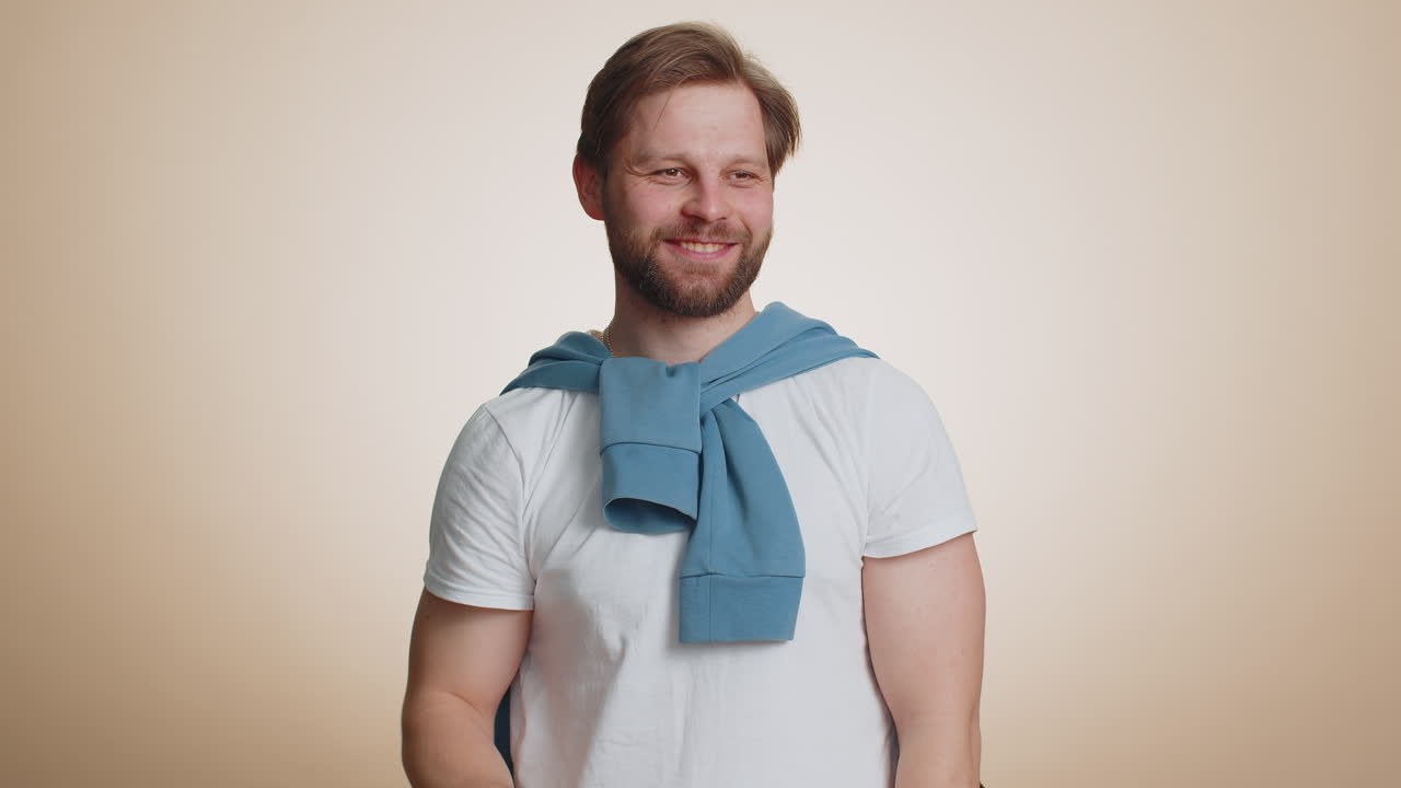 Young man holding hand above eyes forehead peering into distance searching someone waving hello