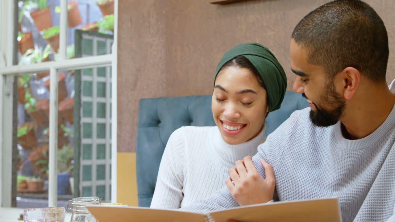 커플이 카페 4k에서 메뉴 카드를 논의합니다.