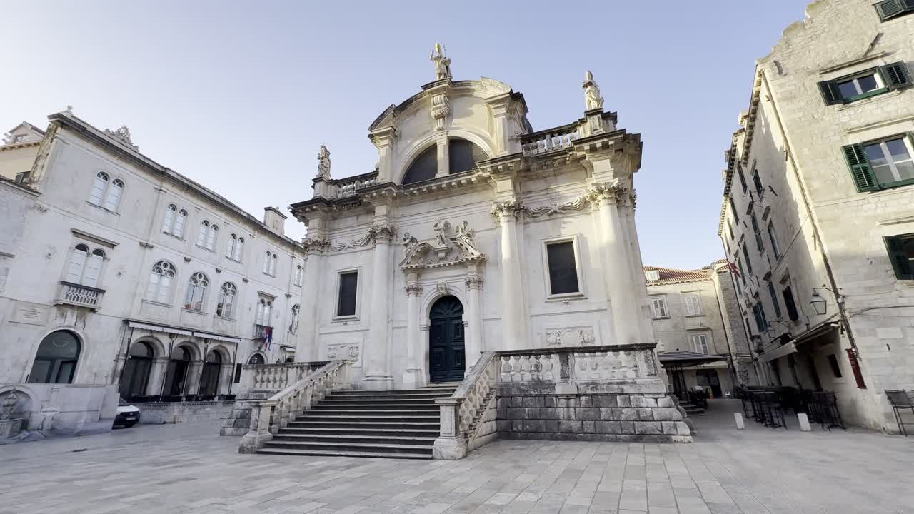B-roll cinematografico della facciata della chiesa di San Biagio nel centro storico di Dubrovnik all'alba con piazza vuota e senza persone, che mette in risalto la splendida architettura barocca in pietra calcarea e l'atmosfera tranquilla