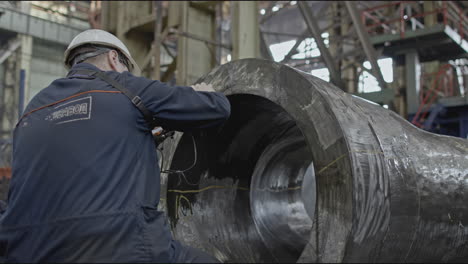 industrial worker inspecting a large metal part