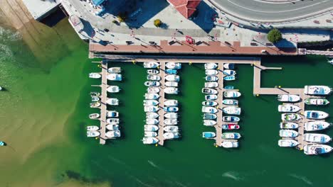 sport boats docked in a harbour while people stroll on the promenade in san vicente de la barquera, cantabria, spain