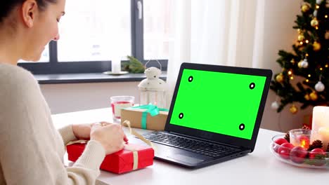 people,-technology-and-online-communication-concept--happy-young-woman-with-gift-box-and-laptop-computer-having-video-call-or-virtual-christmas-party-at-home