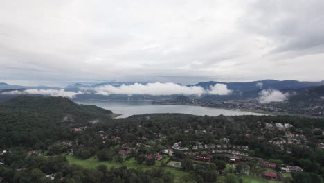 fotografía aérea, dolly up revelando una pequeña ciudad junto a un lago en valle de bravo, méxico
