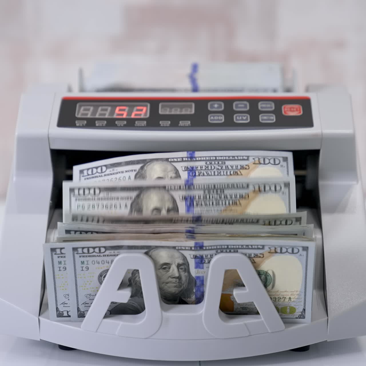 Equipment for counting money. Wad of hundred dollars are counted in a calculating machine. Automatic equipment for banking financial transactions. Female's hand puts money into electronic machine