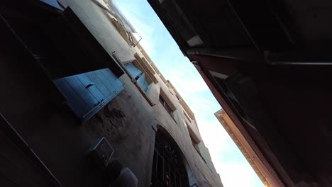 looking up into towering buildings through the alleyways in the old town of venice, italy