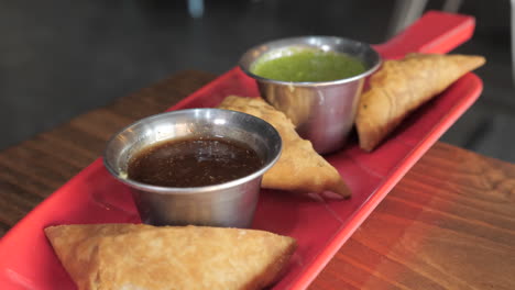 Fork-dips-samosa-into-chutney,-slider-pull-slow-motion-close-up-HD