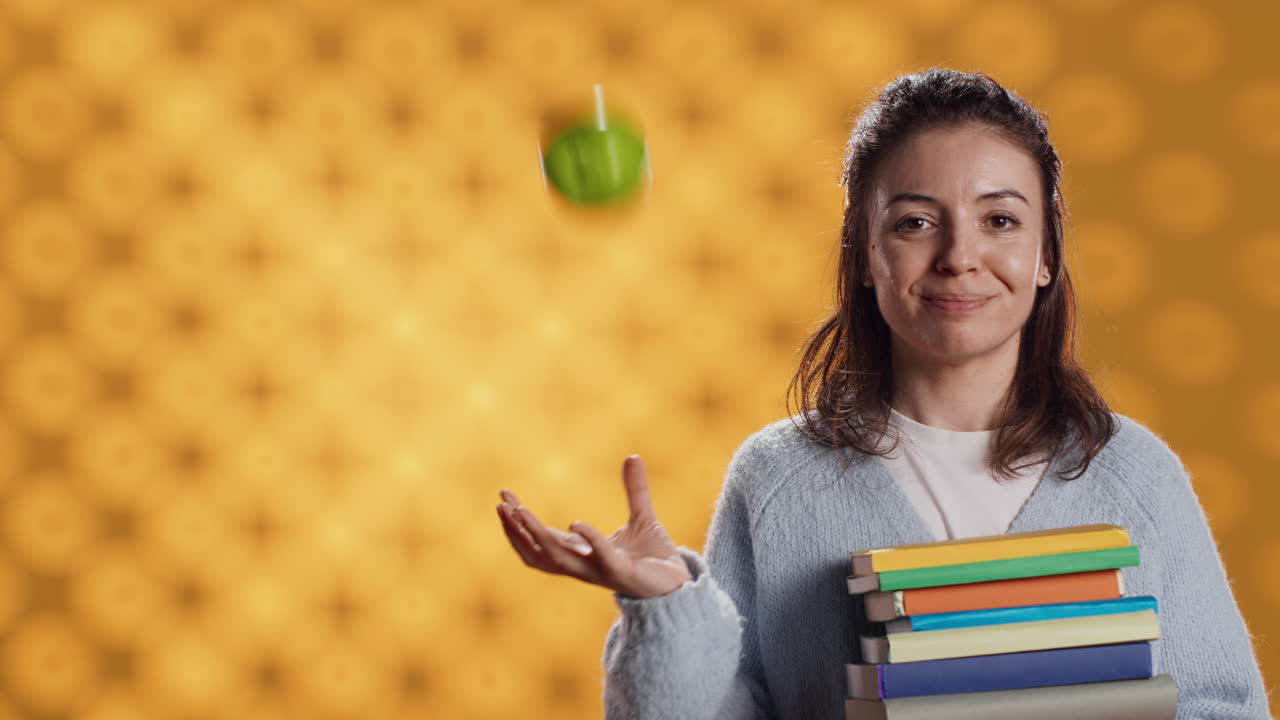 persona alegre sosteniendo libros, jugando con fruta fresca, buen concepto de estilo de vida