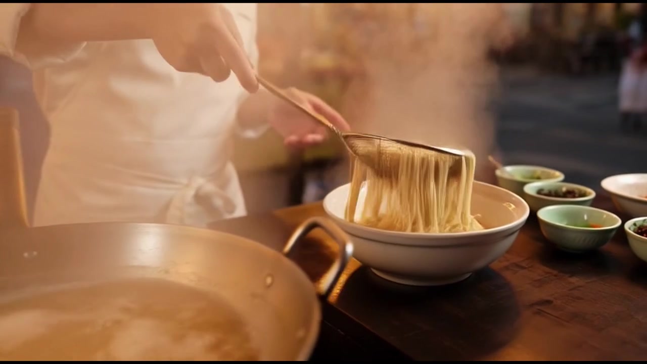 Chef che prepara noodles freschi presso una bancarella di street food all'aperto