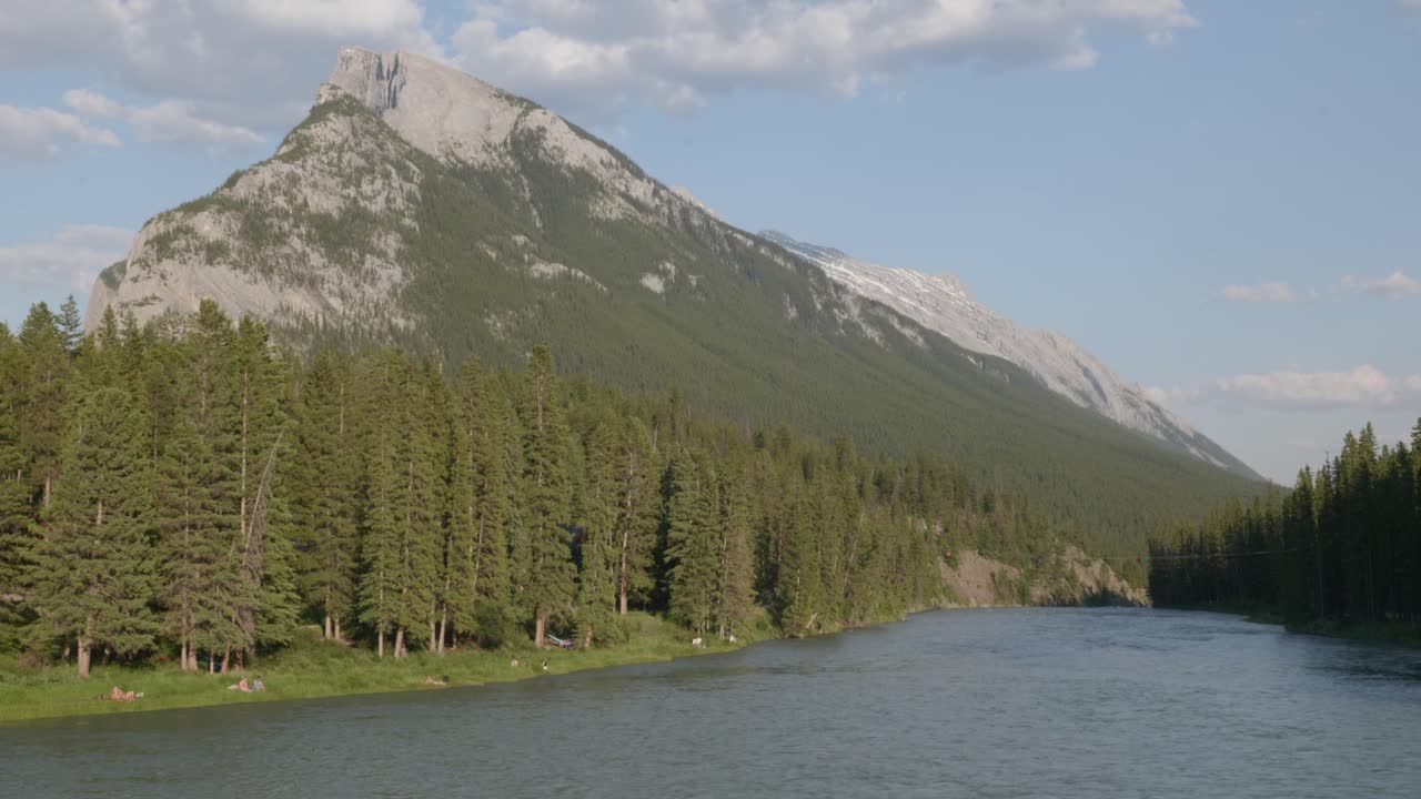 el río bow en el parque nacional banff fluye bajo una montaña altísima bajo un cielo azul.