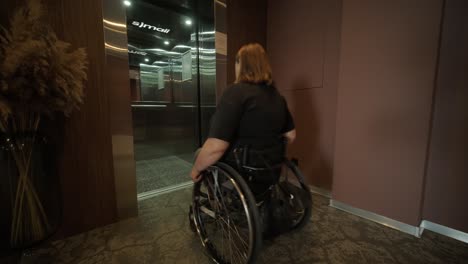 a woman in a wheelchair approaches an elevator in a hotel lobby, showcasing accessible accommodations and modern design. the scene emphasizes mobility, independence, and inclusivity in hospitality.