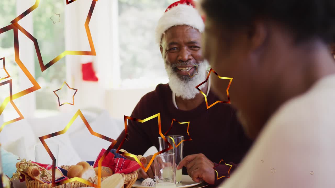 Animação de estrelas sobre família afro-americana com gorros de Papai Noel ceando no Natal.