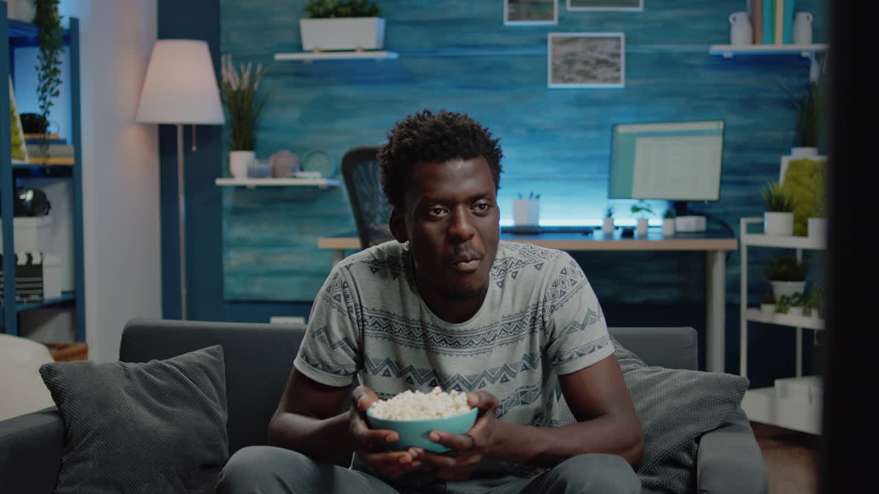 Black adult watching comedy movie on television