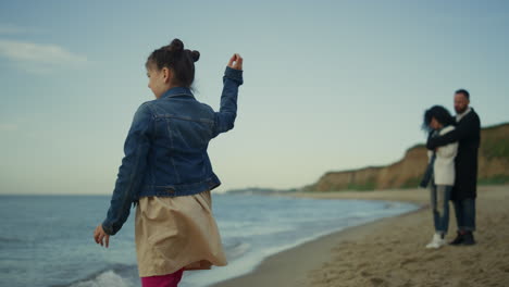 Niña-Jugando-En-La-Playa-En-Un-Viaje-Familiar.-Padres-Pasando-Tiempo-Juntos-En-El-Mar.