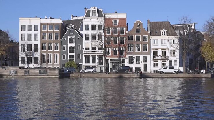 Tipiche case sui canali ad Amsterdam, Paesi Bassi, che si riflettono nel canale antistante in una giornata di sole con cielo azzurro